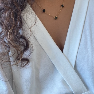 Colar dourado com flores pretas em pescoço com blusa branca