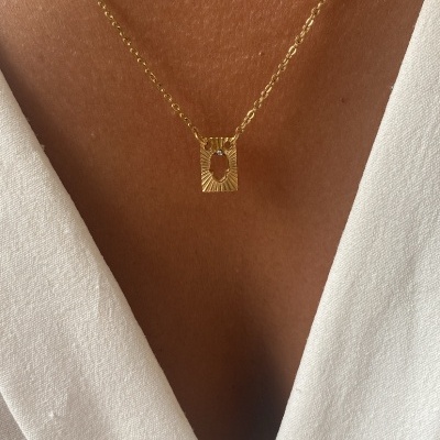 Colar dourado com pendente retangular em pele castanha e camisa branca