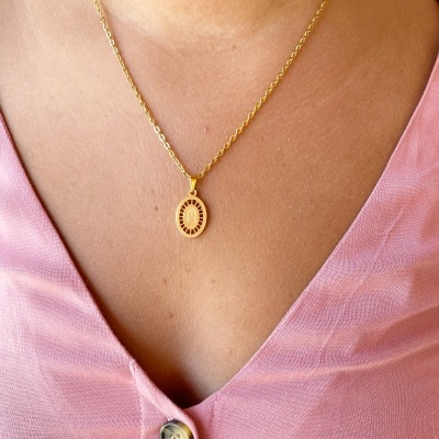 Colar dourado com pendente oval usado com blusa rosa