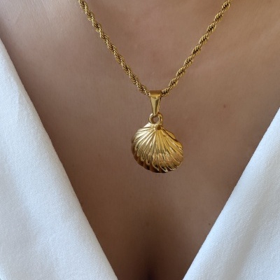 Colar dourado com pingente de concha usado no pescoço