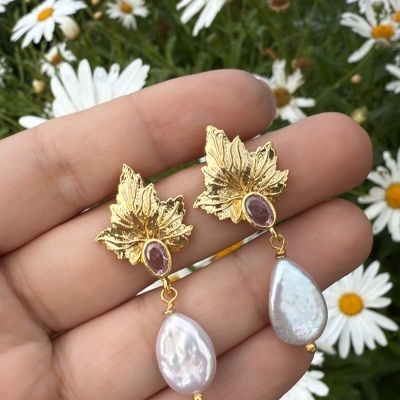 Brincos dourados em forma de folha com pedra rosa e pendente de pérola