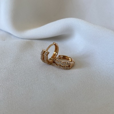 Brincos dourados com pedras sobre tecido branco