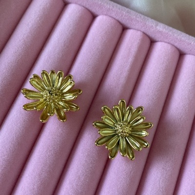 Brincos dourados em forma de flor numa caixa rosa de veludo