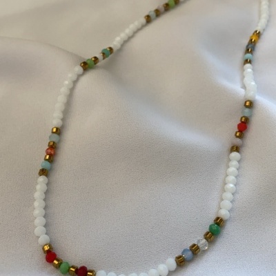 Colar de contas brancas e coloridas sobre tecido branco