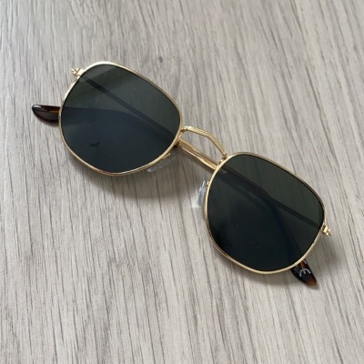 Óculos de sol dourados com lentes escuras sobre madeira clara