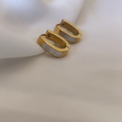 Brincos ovais dourados com faixa branca perolada sobre tecido branco