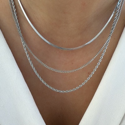 Colares prateados em diferentes estilos usados sobre blusa branca com decote V.