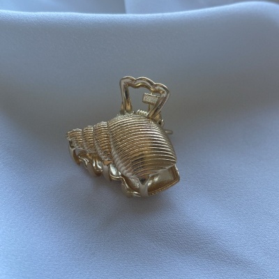 Prendedor de cabelo dourado sobre tecido branco