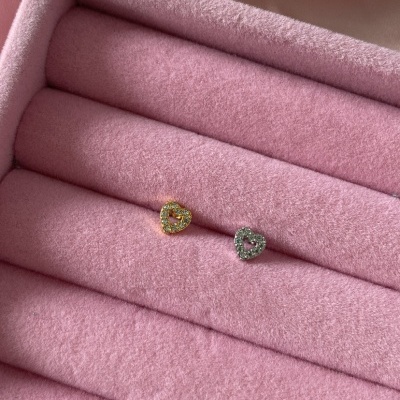 Brincos de coração dourado e prateado com pedras, sobre caixa rosa acolchoada