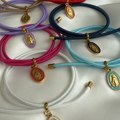 Pulseiras coloridas com pendentes ovalados dourados sobre tecido branco
