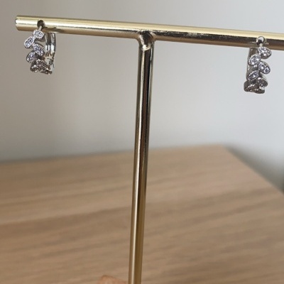 Brincos prateados com cristais pendurados em suporte dourado com base de madeira