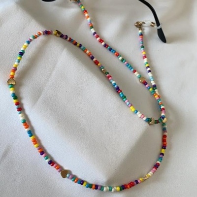 Óculos de sol dourados com lentes escuras e cordão colorido de contas.