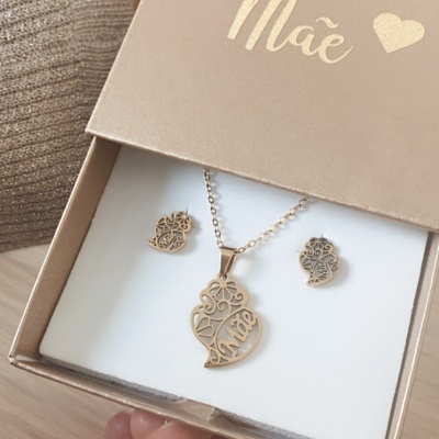 Conjunto de joalharia dourado com pendente e brincos, em caixa bege com palavra 