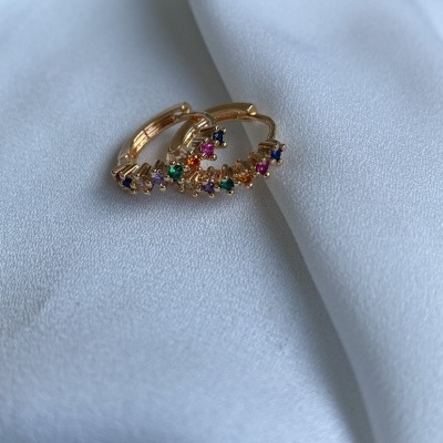 Brincos de argola dourados com pedras coloridas sobre tecido branco