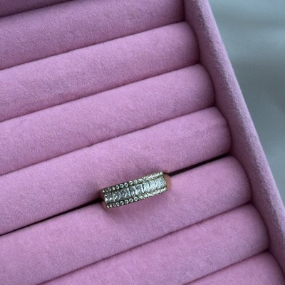 Anel dourado com pedras numa caixa rosa de veludo para joias