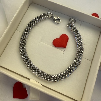 Pulseira de corrente prateada numa caixa branca com corações vermelhos