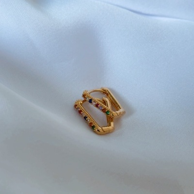 brincos dourados quadrados com pedras coloridas em tecido branco