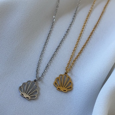 Colares com pendentes em forma de concha, um prateado e outro dourado sobre tecido branco