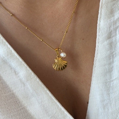 Colar dourado com pendente de concha e pérola com camisa branca