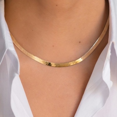 Colar metálico dourado liso em pescoço com camisa branca