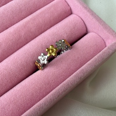 anel metálico com flores prateado e dourado numa caixa de veludo rosa