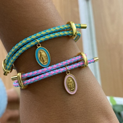 Braceletes trançados em tecido azul com amarelo e rosa com azul, com medalhas douradas penduradas no pulso