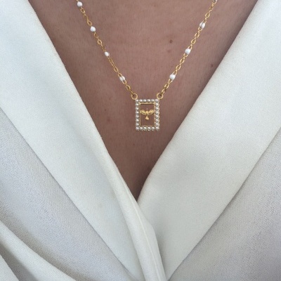 Colar dourado com pérolas e pendente retangular com figura dourada no centro