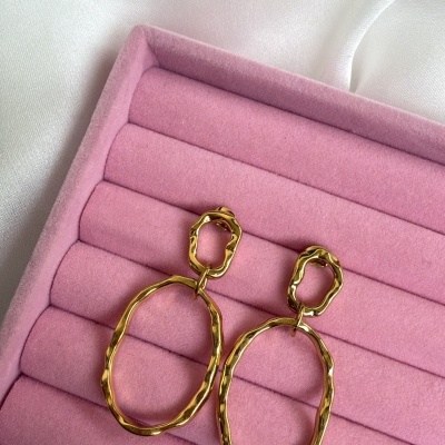 Brincos dourados em forma oval em caixa de veludo rosa