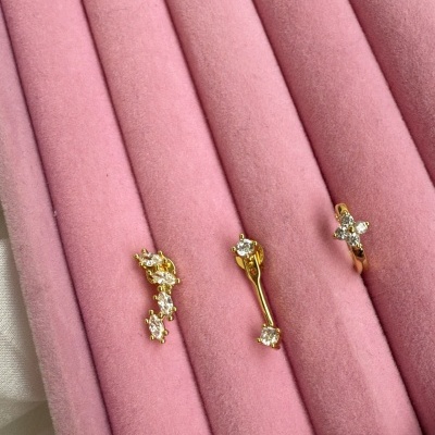 Três brincos dourados com pedras brilhantes em veludo rosa