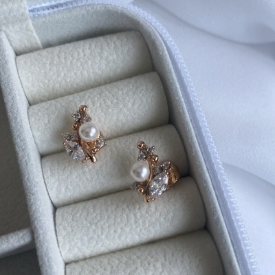 Brincos dourados com pérolas e pedras em caixa de veludo cinzenta clara