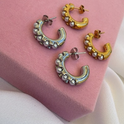 Dois pares de brincos meia argola com pérolas, um prateado e outro dourado sobre veludo rosa