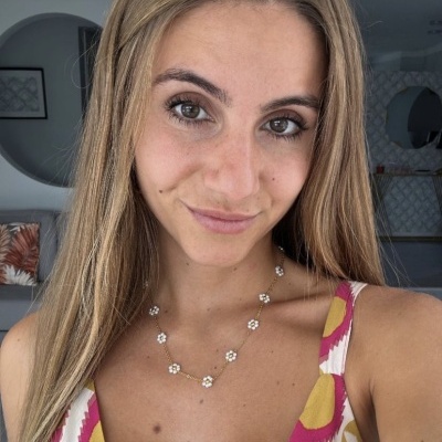 Mulher loira com vestido colorido e colar florido em ambiente interior moderno