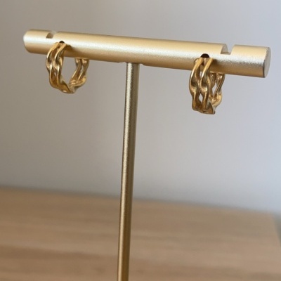 Brincos dourados entrelaçados em suporte dourado