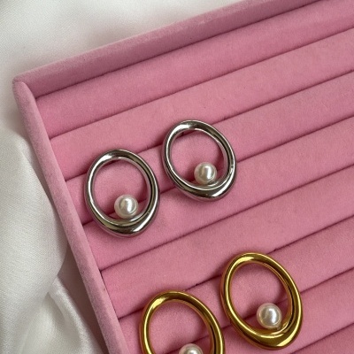 Dois pares de brincos ovais com pérolas numa caixa rosa e fundo branco