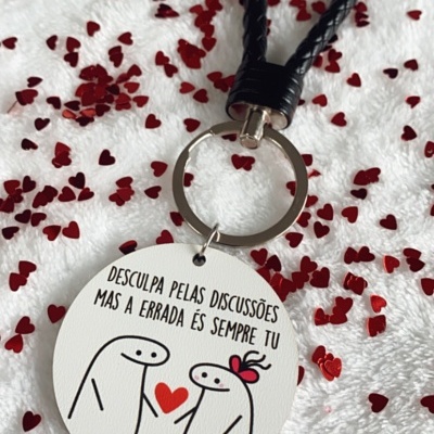 Porta-chaves com pendente redondo branco com desenho e texto em português sobre fundo branco com corações vermelhos