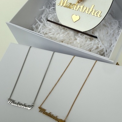 Colares prateados e dourados com pendente Madrinha junto a flores secas e caixa Feliz Páscoa