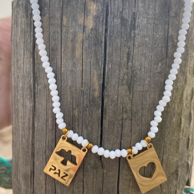 Colar de contas brancas com pendentes de madeira retangulares com a palavra PAZ e coração