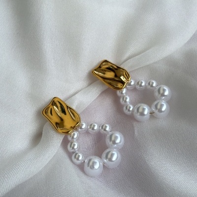 Brincos dourados com pérolas em tecido branco