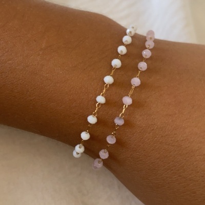 braceletes dourados com contas brancas e cor-de-rosa no pulso