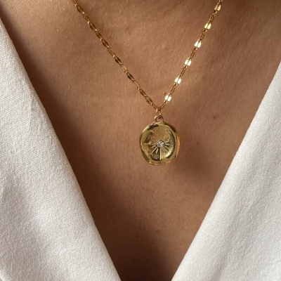 Colar dourado com pingente redondo e roupa branca