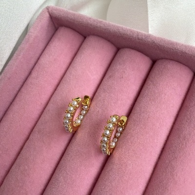 Brincos de pérolas em estojo rosa de veludo, fundo branco