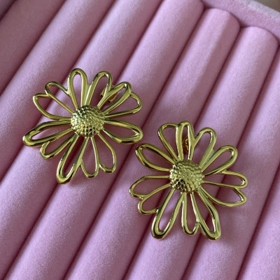 Brincos florais dourados sobre almofada rosa