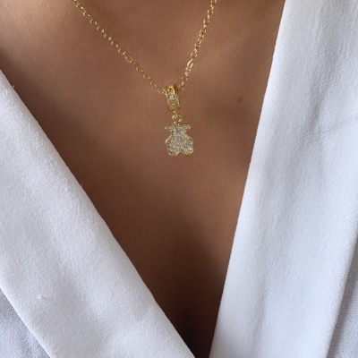 Colar dourado com pendente de ursinho cravejado usado no pescoço