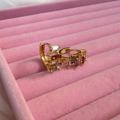 Brincos dourados com pedras transparentes numa caixa de veludo cor-de-rosa