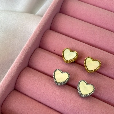 Brincos em forma de coração com molduras dourada e prateada numa caixa de veludo rosa