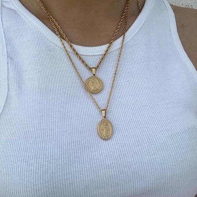 Colar dourado com dois pendentes redondos usado com t-shirt branca canelada.