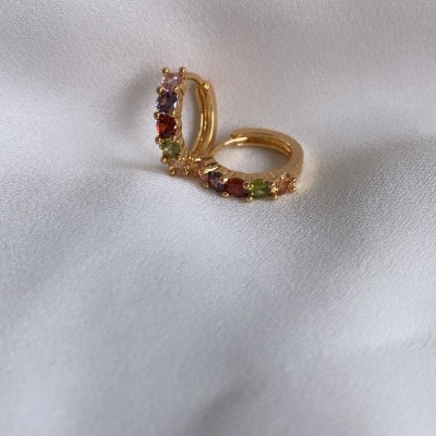 Brincos dourados em argola com pedras coloridas sobre tecido branco