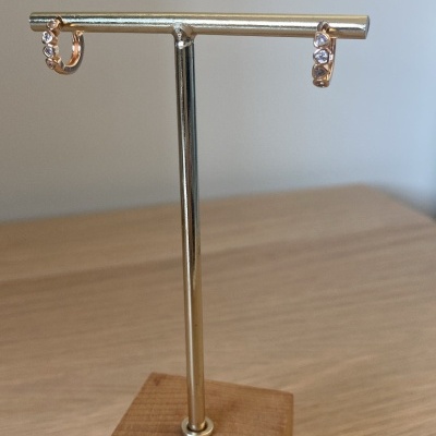 Par de brincos dourados em suporte metálico com base de madeira