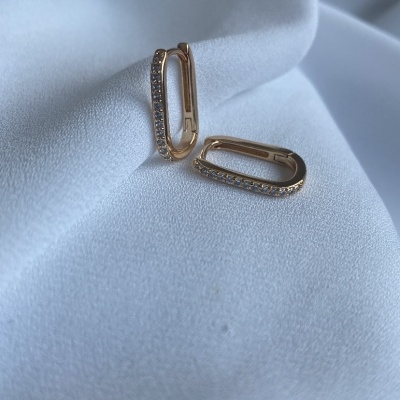 Par de brincos dourados com pedras sobre tecido branco