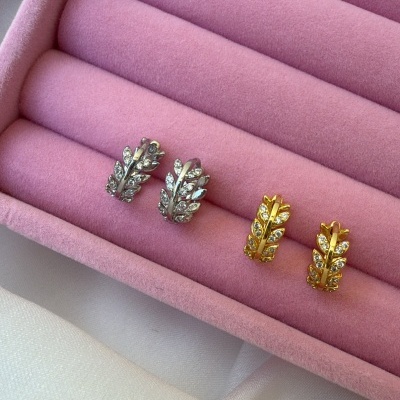 Dois pares de brincos em formato de folhas, prateado e dourado, com pedras, caixa de veludo rosa